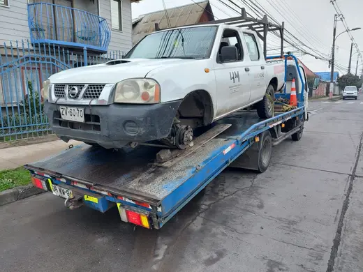 Grúa plataforma con camioneta Nissan blanca