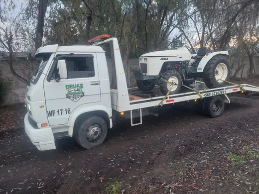 Traslado de tractor pequeño en grúa plataforma