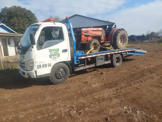 Traslado de tractor rojo en grúa plataforma