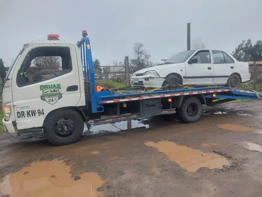 Remolque de auto sedán blanco en zona rural