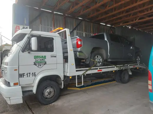 Grúa plataforma con camioneta gris bajo techo