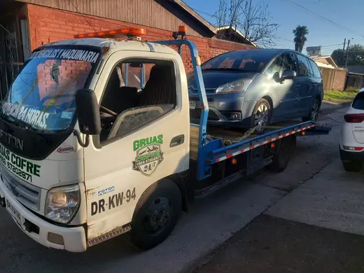 Grúa Cofré trasladando auto gris al anochecer